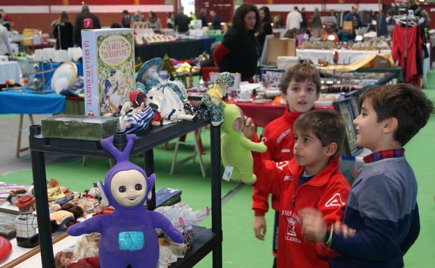 Tres niños ensimismados con los juguetes de El Mercado de Arroyo. /Jota de la Fuente