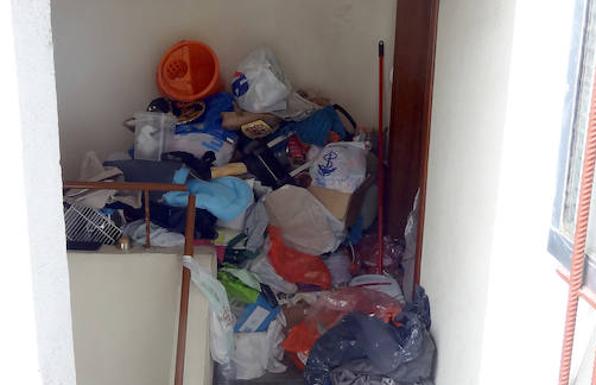 Basura acumulada en el rellano del piso de la mujer y la intervención (derecha) para sacarla del bloque de la calle Portillo de Balboa/J. S: