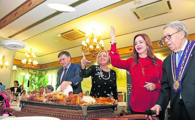Francisco Vázquez, Paloma Sanz y Silvia Clemente participan el ritual del cochinillo durante el almuerzo navideño. /El Norte
