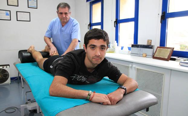 Santiago Llorente recibe un masaje de su padre en su consulta de La Lastrilla. /Antonio Tanarro