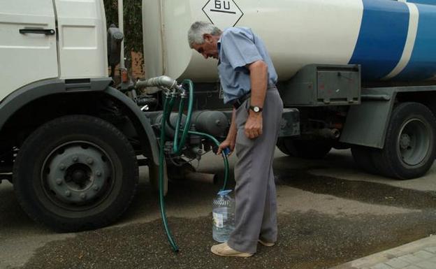 Un hombre rellena una garrafa de agua de un camión cisterna. /LUIS CALLEJA